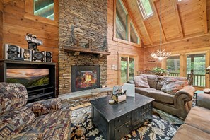 Ein gemütliches Blockhaus-Interieur mit Kamin, bequemen Sitzgelegenheiten und einem Fernseher.