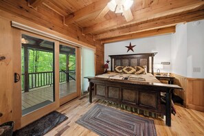 Ein Schlafzimmer einer Holzhütte mit einem großen Bett, einer Stern-Dekoration an der Wand und einer Glastür, die auf eine Terrasse führt.