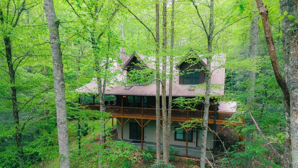 A two-story cabin surrounded by dense forest. - Log Heaven (Banner Elk)