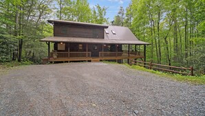 A rustic cabin with a porch, surrounded by a forest. - Log Heaven (Banner Elk)