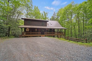 Eine rustikale Holzhütte mit Veranda, umgeben von einem Wald.