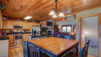 A spacious kitchen with wooden cabinets, a large dining table, and a stone fireplace.