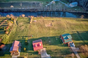 Vista aérea de uma propriedade rural com dois edifícios principais, um celeiro e uma casa com telhado vermelho.
