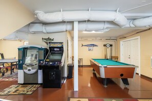 A recreational room with a pool table, a pinball machine, and a fish mounted on the wall. - New River Ramble (Todd)