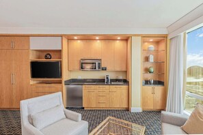 A compact hotel room with a kitchenette, a flat-screen TV, a sofa, and a large window offering a view. - Trump Hotel Las Vegas Strip View Studio (Las Vegas)