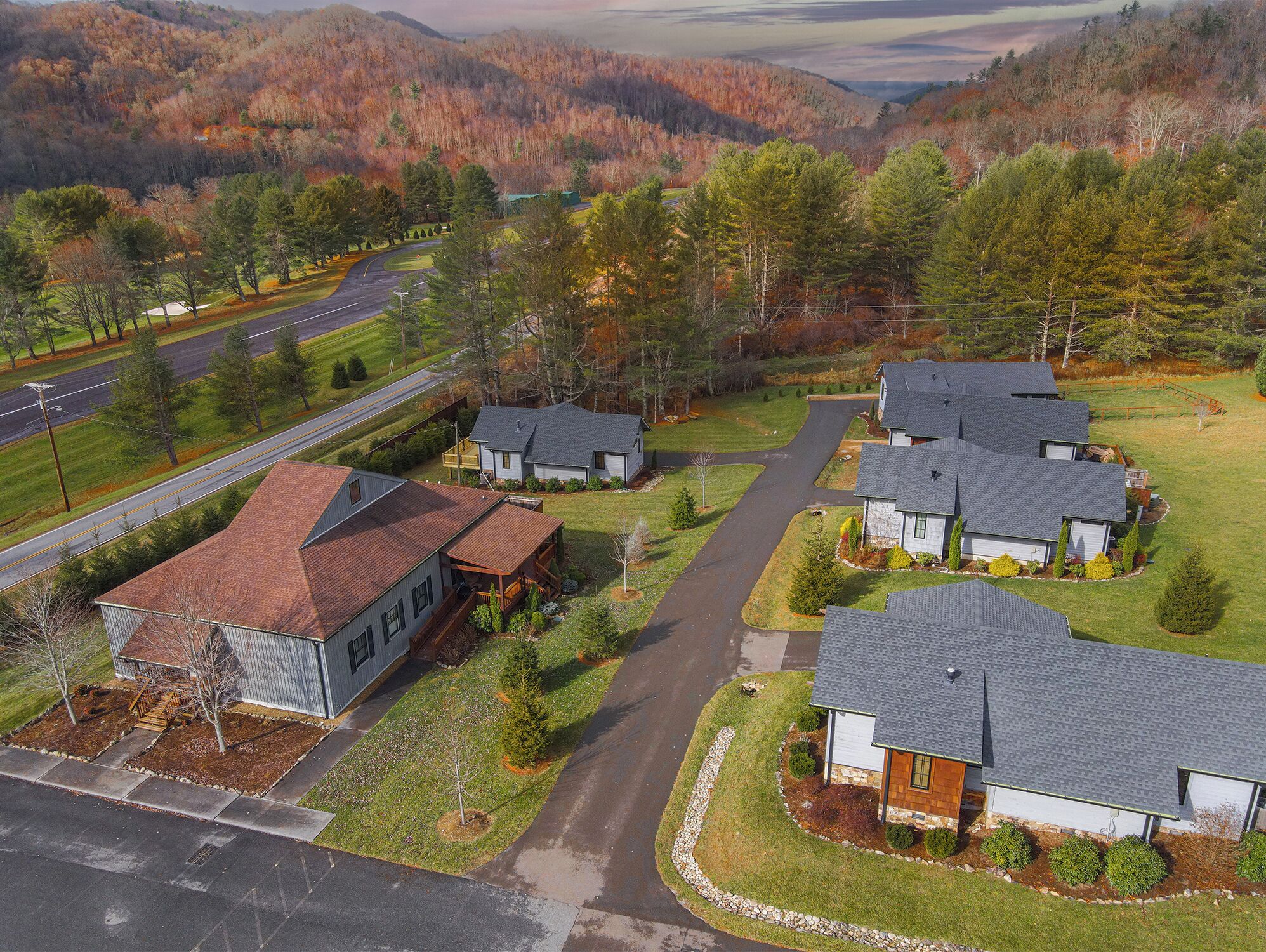 A residential area with multiple houses, a road, and a hilly landscape in the background.