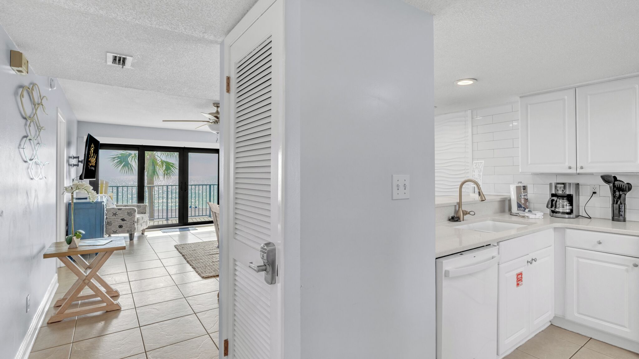 A modern kitchen with white cabinets, a sink, and a coffee maker.