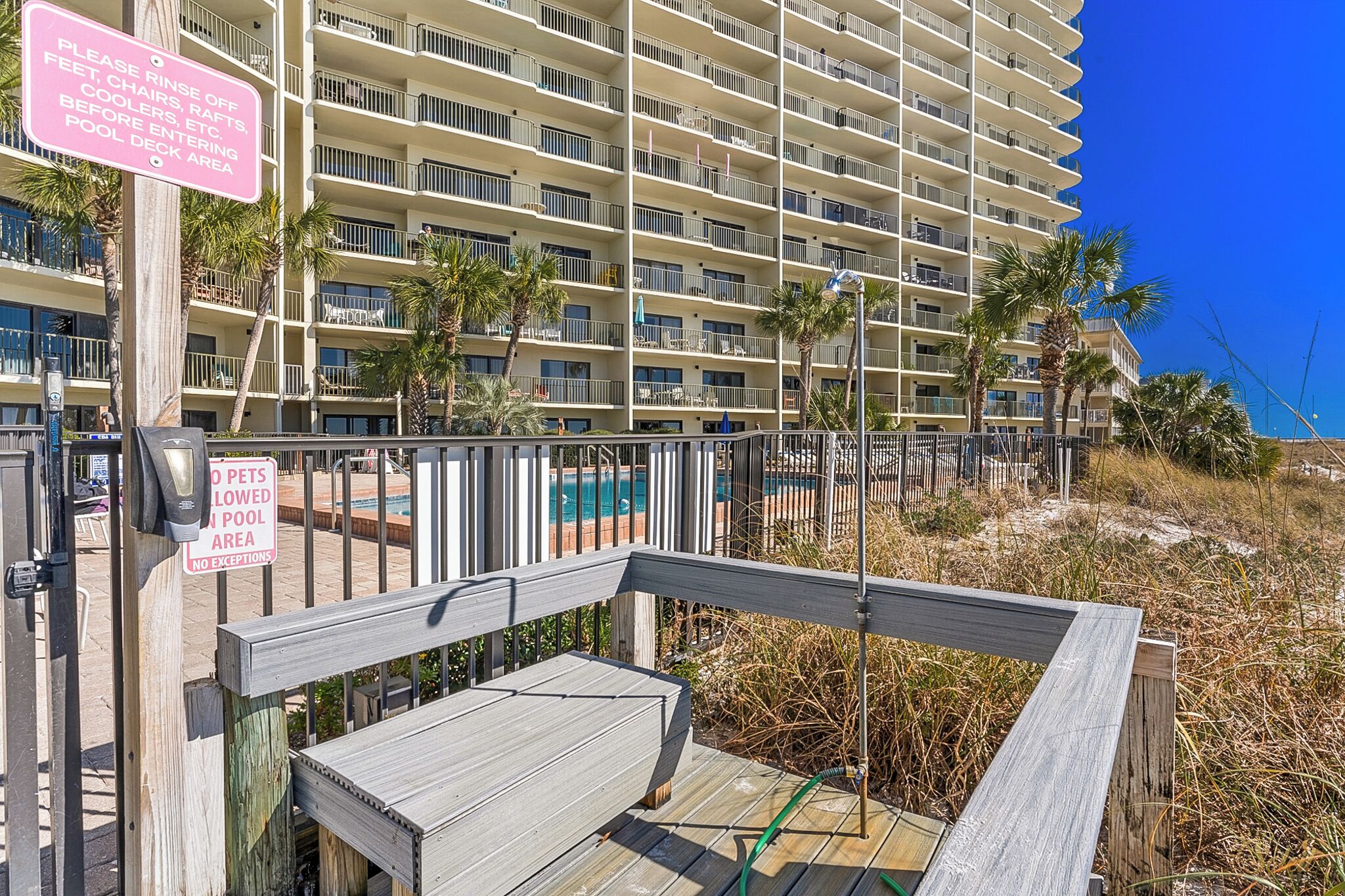 Un hotel de varios pisos con balcones, una zona de piscina y una terraza de madera.