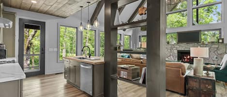 A spacious kitchen with a central island, large windows, and a stone fireplace.