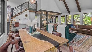 A spacious living area with a wooden dining table, leather chairs, a sofa, and a staircase. - Three Bears Retreat at Monteagle (Banner Elk)