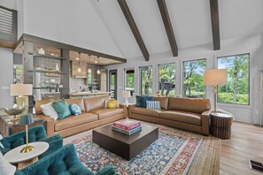 Ein geräumiges Wohnzimmer mit einem großen braunen Ledersofa, einem Couchtisch und einem gemusterten Teppich.