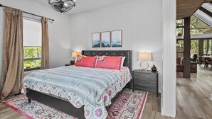 A bedroom with a large bed, a chandelier, a view of the outdoors, and a dining area. - Three Bears Retreat at Monteagle (Banner Elk)