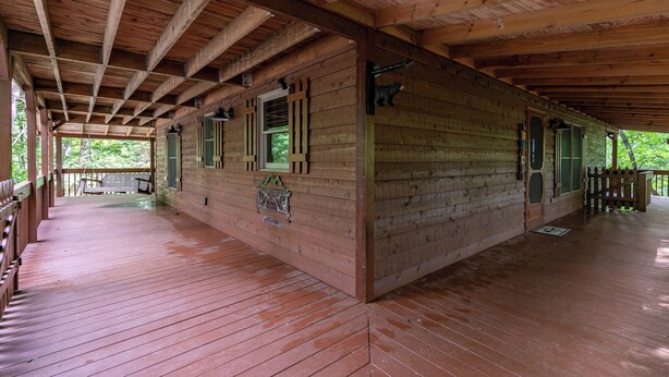 A covered wooden building with a porch, wooden beams, and a green door. - Heavens Hideaway (Ferguson)