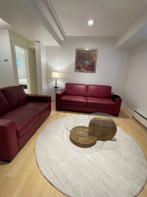 Ein Wohnzimmer mit einem roten Ledersofa, einem Glastisch und einer Lampe.
