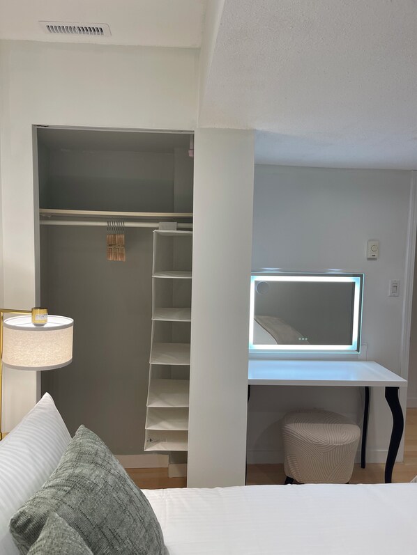Ein Schlafzimmer mit Bett, Nachttischlampe, Kleiderschrank und Schreibtisch mit integrierter Beleuchtung.