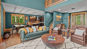 A spacious living area with a sofa, coffee table, and a dining table with chairs. - Bull & Bear at Eagles Nest (Banner Elk)