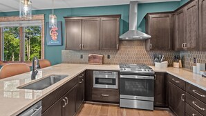 A modern kitchen with dark wood cabinets, stainless steel appliances, and a tiled backsplash. - Bull & Bear at Eagles Nest (Banner Elk)