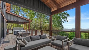 A covered outdoor deck with a wooden ceiling, a barbecue grill, and a seating area with sofas and chairs. - Bull & Bear at Eagles Nest (Banner Elk)