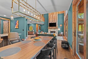 A modern interior with a dining area, a fireplace, and a TV mounted on a stone wall.
