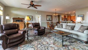 A spacious living room with a fireplace, leather armchairs, a sofa, and a dining area in the background. - Sugarjax at The Reserve (Banner Elk)