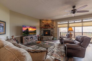 Una sala de estar con chimenea, televisión y un balcón con vistas.