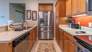A kitchen with wooden cabinets, stainless steel appliances, a dishwasher, and a refrigerator. - Sugarjax at The Reserve (Banner Elk)