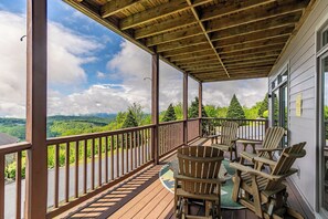 Una terraza de madera con sillas Adirondack con vistas a un paisaje pintoresco.