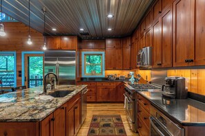 A modern kitchen with wooden cabinets, stainless steel appliances, and a granite countertop.