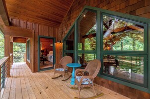 Una cabaña de madera con un porche, mecedoras y una mesa.