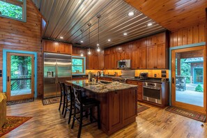 Una cocina amplia con armarios de madera, electrodomésticos de acero inoxidable y una isla grande con taburetes de bar.