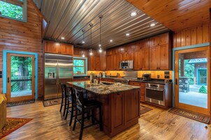 Una cocina amplia con armarios de madera, electrodomésticos de acero inoxidable y una isla grande con taburetes de bar.