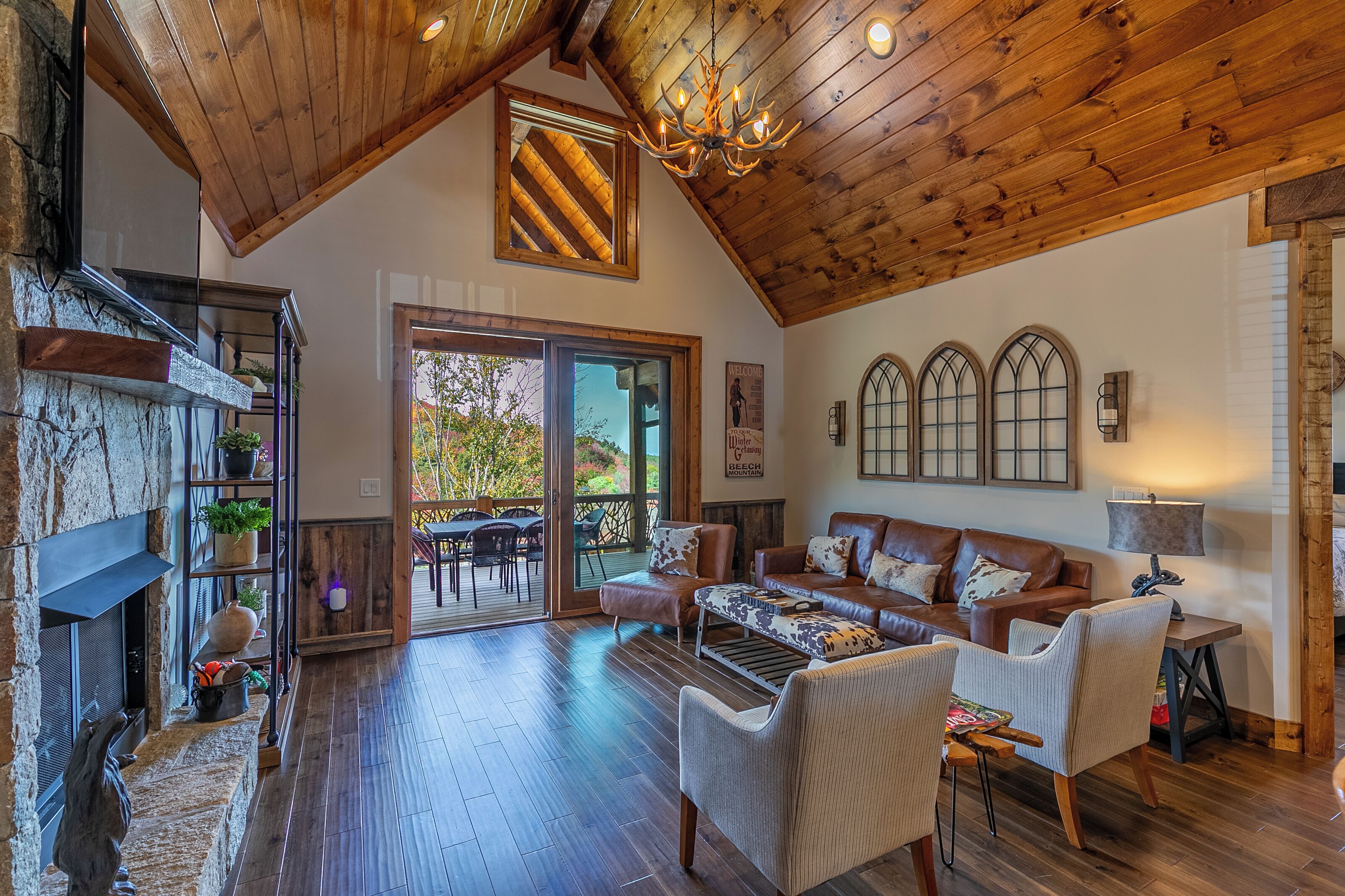 A spacious living area with a wooden ceiling, a fireplace, a sofa set, and a dining table.