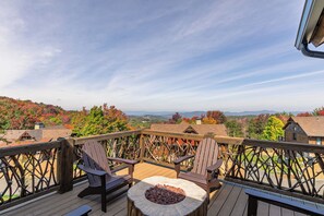 A wooden deck with Adirondack chairs and a fire pit, overlooking a scenic landscape with autumn foliage and distant mountains. - Cabearnet at Eagles Nest (Banner Elk)