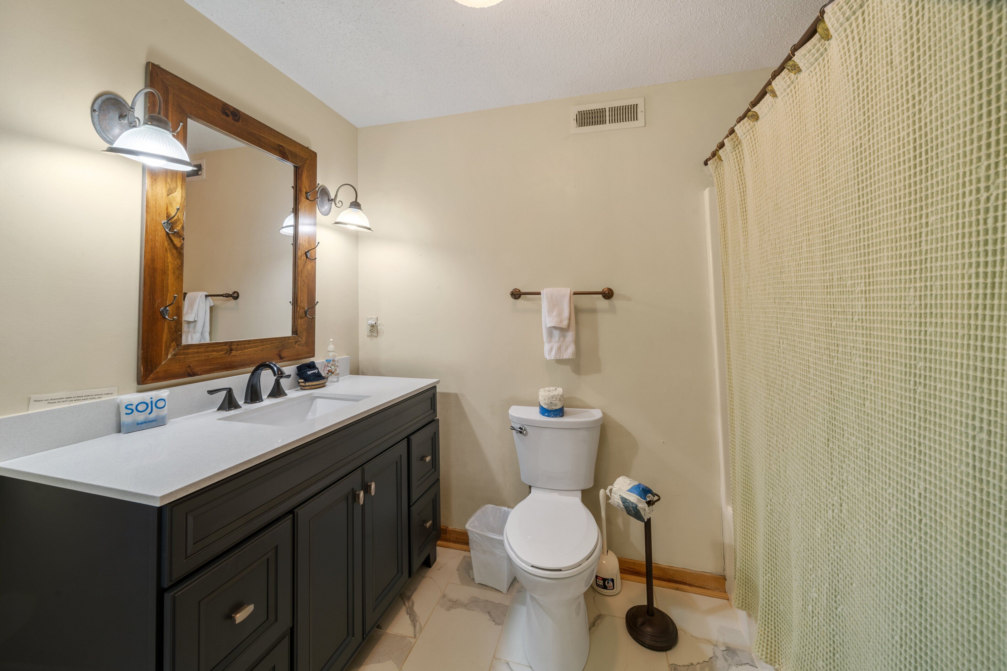 A bathroom with a double sink vanity, a toilet, and a shower curtain.