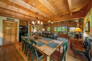 A wooden interior with a dining area, kitchen, and a view of the outdoors. - Appalachian Satisfaction (Banner Elk)