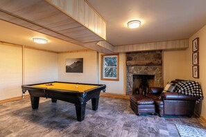 A pool table in a room with a stone fireplace, leather furniture, and a framed picture on the wall. - Parkway Hideout (Boone)