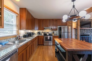 A modern kitchen with wooden cabinets, granite countertops, stainless steel appliances, and a central island. - Parkway Hideout (Boone)