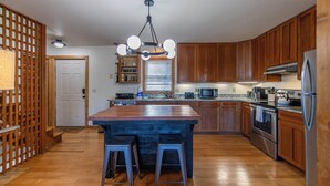 A modern kitchen with wooden cabinets, stainless steel appliances, and a central island with stools. - Parkway Hideout (Boone)