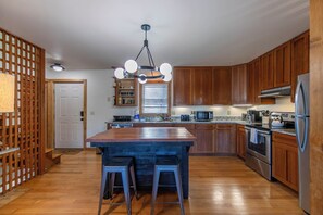 A modern kitchen with wooden cabinets, stainless steel appliances, and a central island with stools. - Parkway Hideout (Boone)