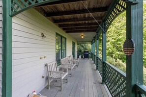 A covered porch with wooden benches and a grill. - Parkway Hideout (Boone)