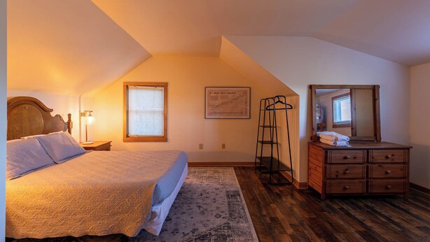 A bedroom with a bed, a dresser, a mirror, a window, and a map on the wall. - Parkway Hideout (Boone)