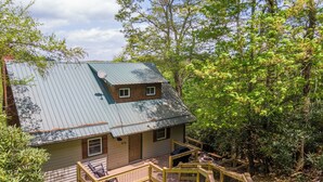 A cabin with a metal roof, wooden deck, and a small porch area. - Parkway Hideout (Boone)