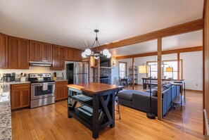 A spacious kitchen with wooden cabinets, a central island, and a stone fireplace. - Parkway Hideout (Boone)