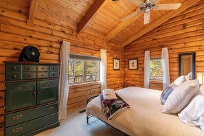 Une chambre dans une cabane en bois, avec un lit, une commode et des fenêtres.