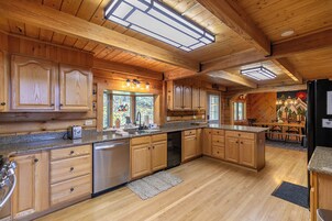 Una cocina amplia con armarios de madera, encimera de granito y lavavajillas.