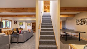 A multi-level room with a carpeted staircase, a foosball table, a ping pong table, and a sofa. - Angels Envy (Lenoir)