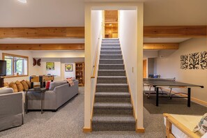 A multi-level room with a carpeted staircase, a foosball table, a ping pong table, and a sofa. - Angels Envy (Lenoir)