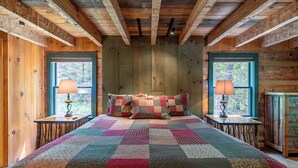 A wooden cabin bedroom with a large bed, two windows, and a quilt. - Paradise Found Newly Updated Cabin (Vilas)