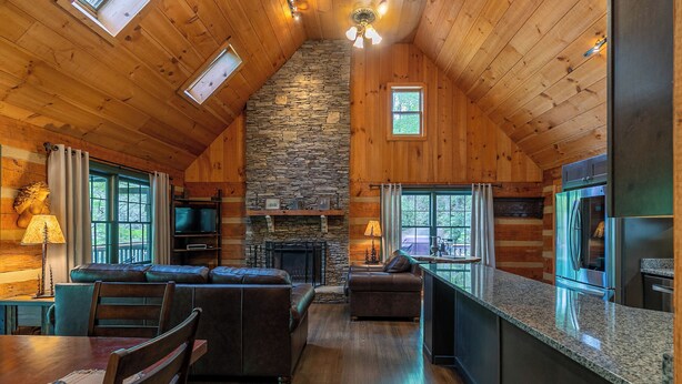 A cozy cabin interior with a stone fireplace, wooden ceiling, and a stone wall. - Paradise Found Newly Updated Cabin (Vilas)