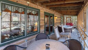 A covered outdoor area with wooden walls, large windows, and a hot tub. - Paradise Found Newly Updated Cabin (Vilas)